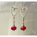A pair of earrings featuring shaped argentium wire hearts from which red crystal beads dangle. For Valentine's Day, or any day!